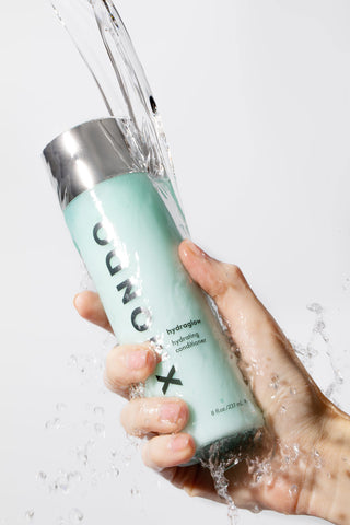 Hand holding Hydraglow hydrating conditioner by XMONDO Hair