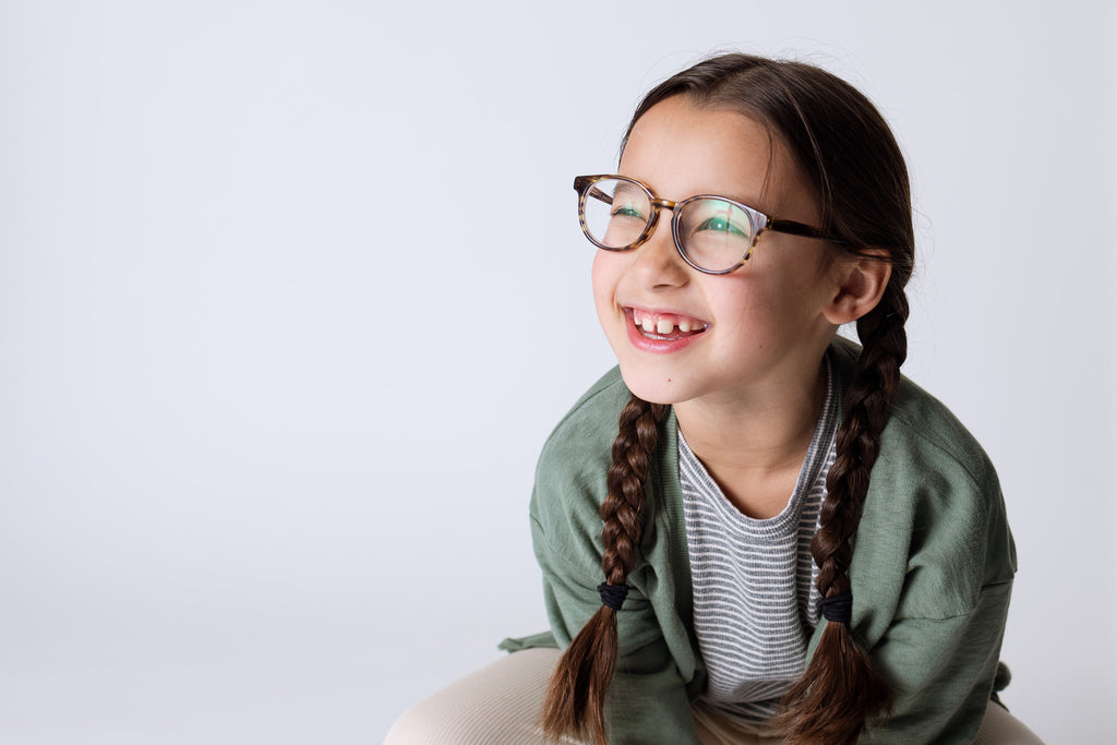 smiling girl crouching and wearing a green cardigan over striped shirt