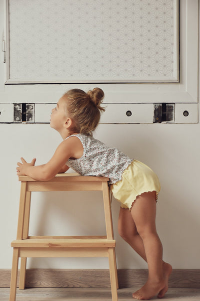 young girl leaning on stool wearing lowland kids summer sleep set