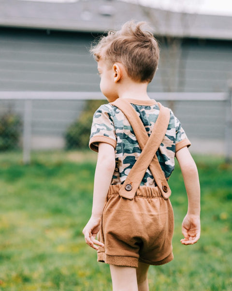 young boy wearing Lowland Kids overalls with tshirt