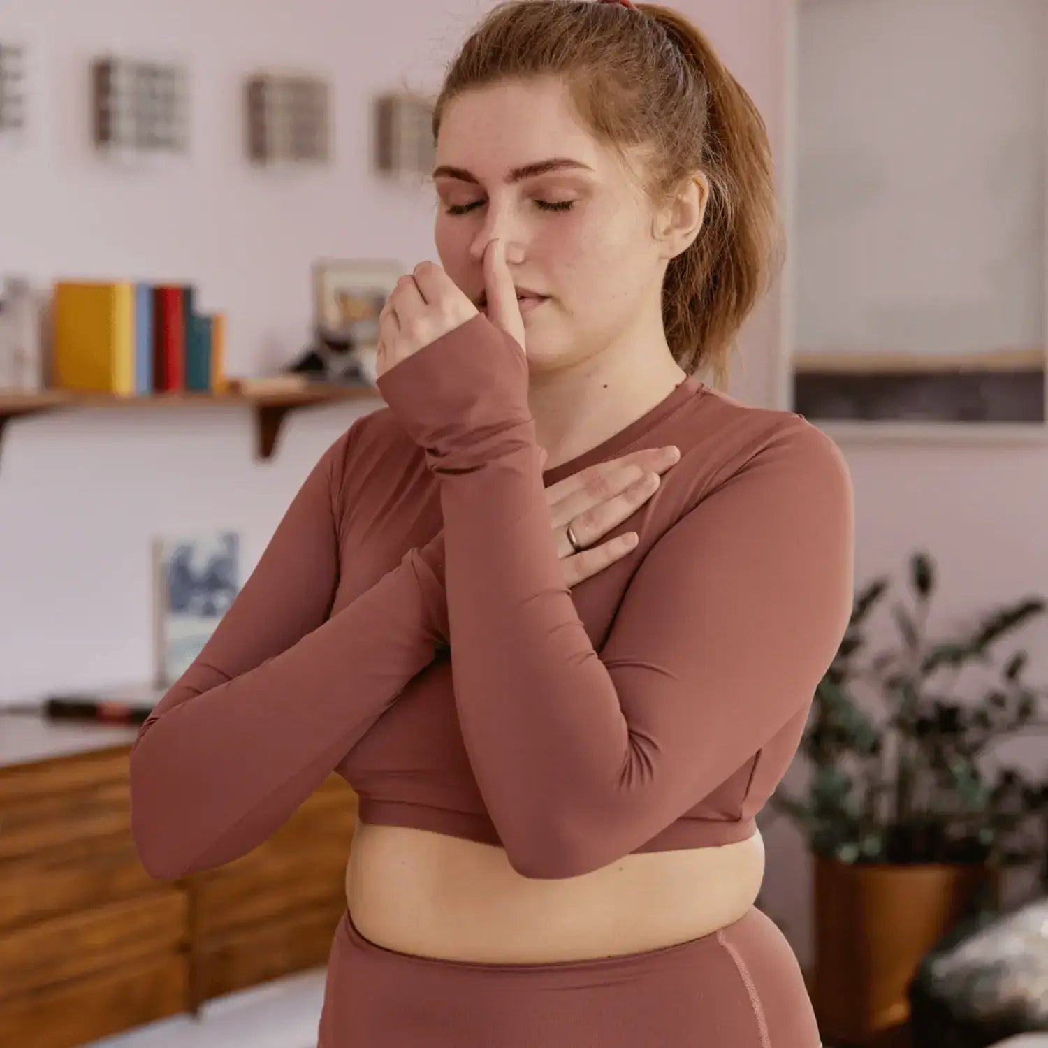 Woman demonstrating alternate nostril breathing, a technique to activate the vagus nerve for sleep improvement.