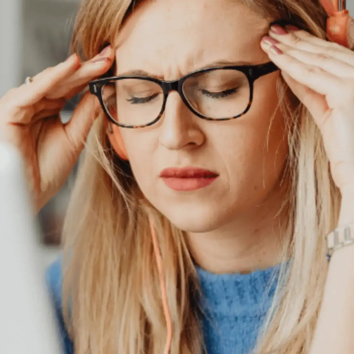 A stressed woman with glasses pressing her temples, representing the impact of stress and how turmeric can help alleviate it.