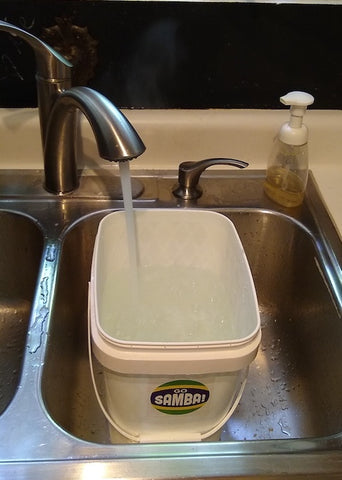White bucket in a sink with a Go Samba sticker on it!
