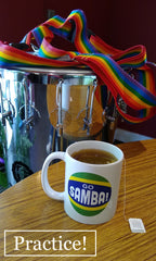 Mug of tea with Go Samba logo sitting on a table. Timbal and timbal strap in the background.