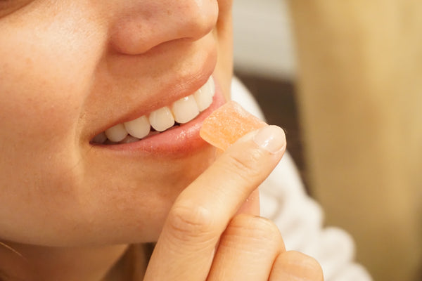 A smiling woman eating a CBD gummy