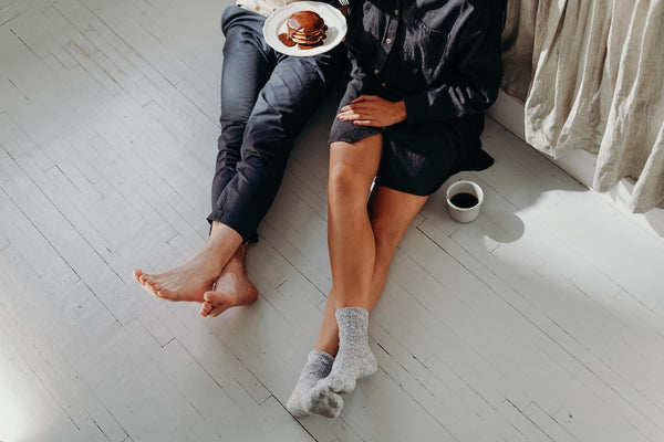 a man and a woman sitting down on the floor next to their bed