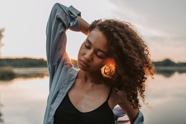 A young woman with curly hair touching her hair