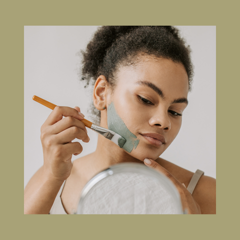 woman painting on a face mask in mirror