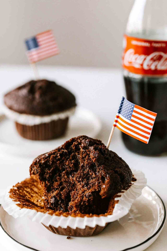  mini American flag on toothpick in a bitten chocolate cupcake sitting on a plate