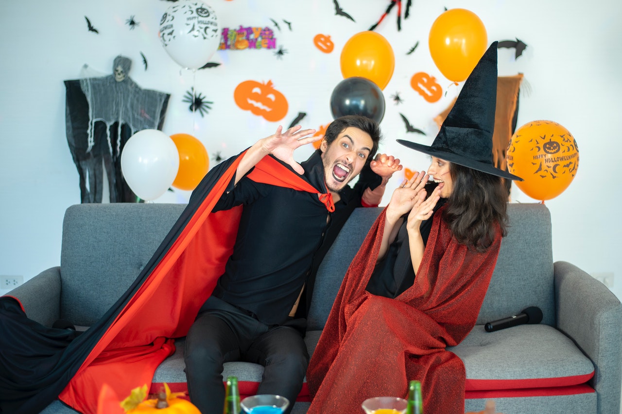 A couple sitting on a couch and wearing halloween costumes