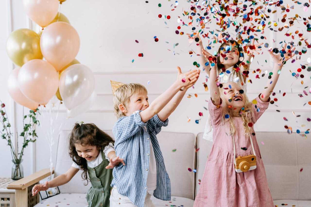 four children throw multicolored confetti in the air