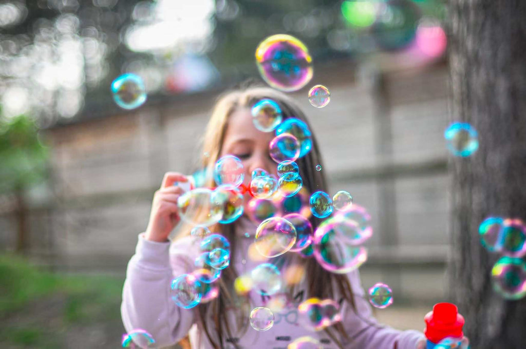 Girl blows bubbles outside