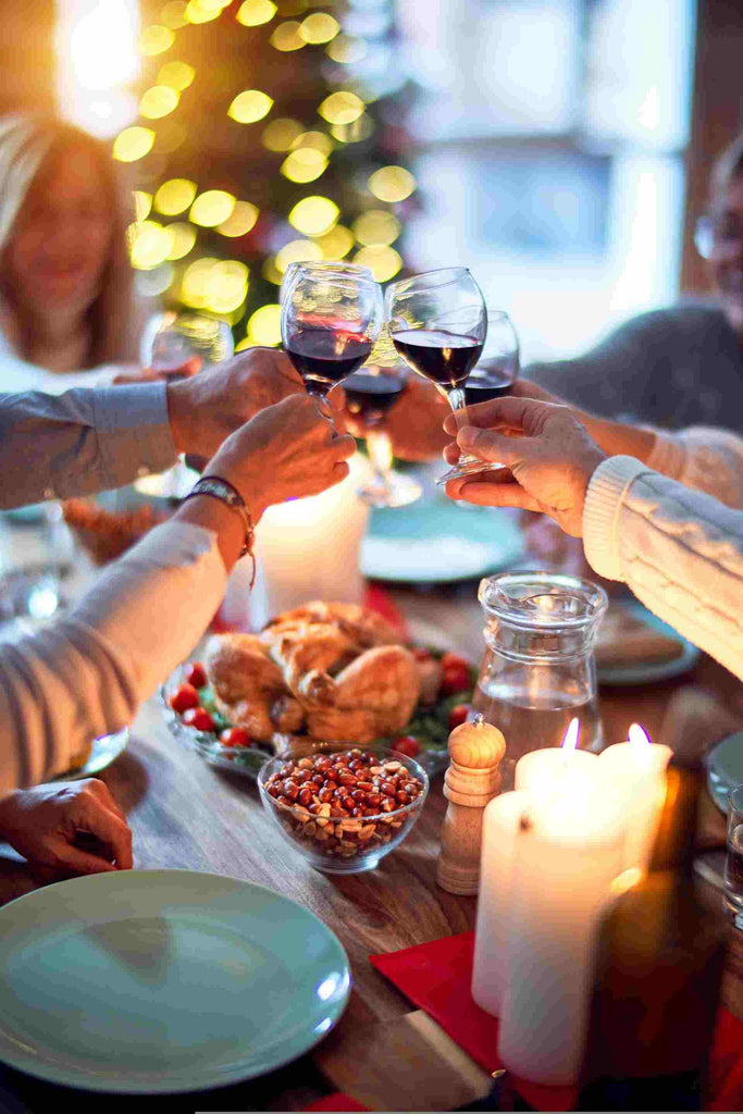 guests giving a toast with glasses of red wine at a dinner party