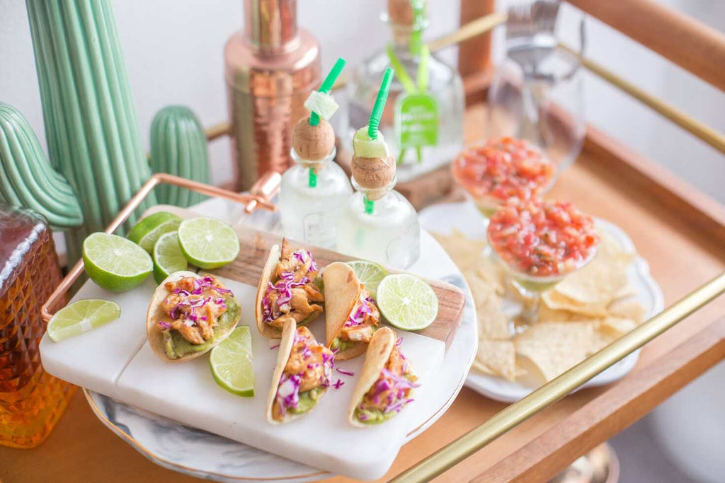 Mini tacos, nachos, and drinks on a serving tray.