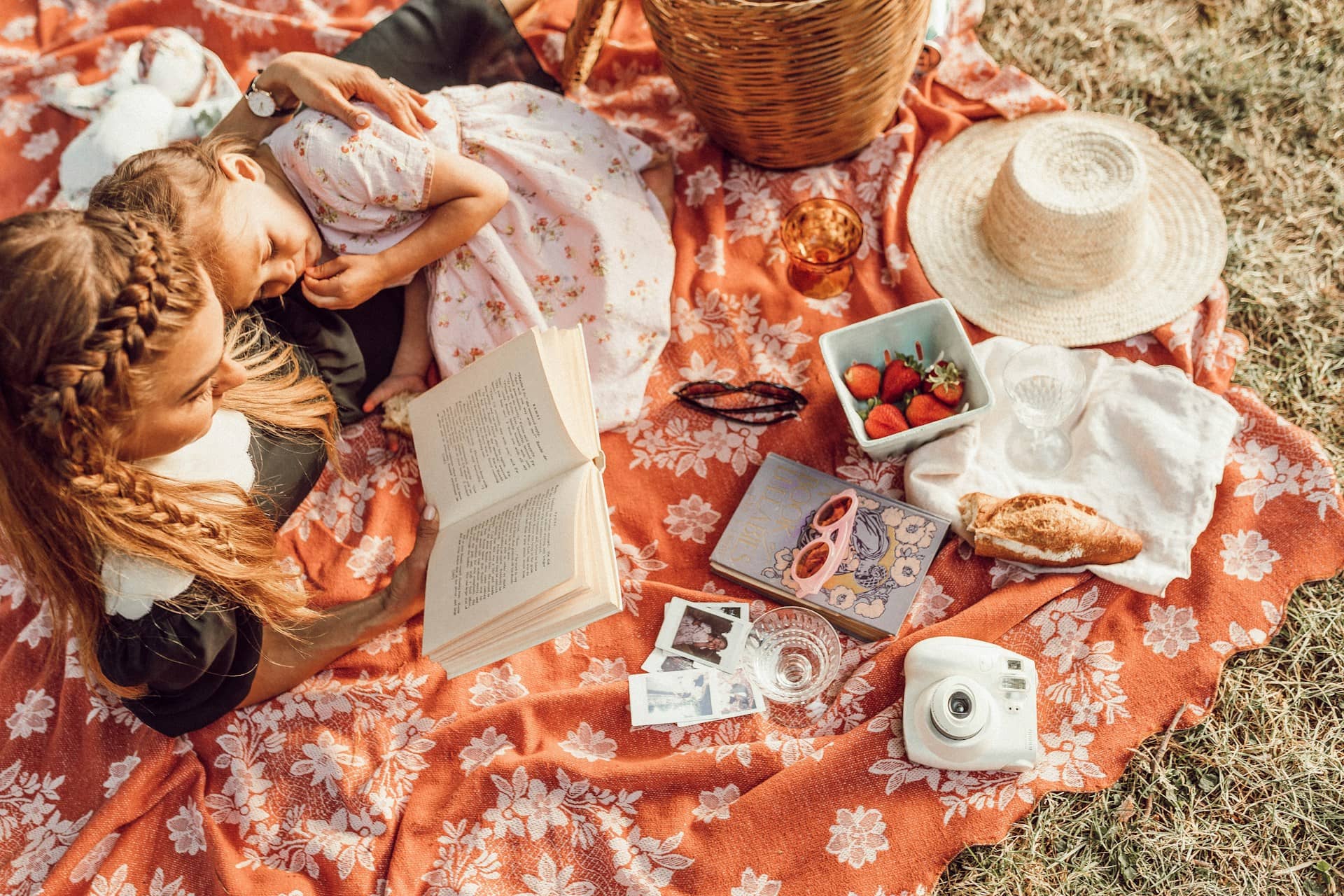 A woman is reading to a child while having a picnic