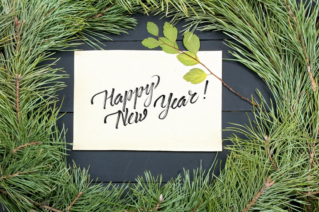 A white “Happy New Year” sign in an evergreen wreath