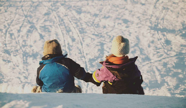 Two kids holding hands in snow
