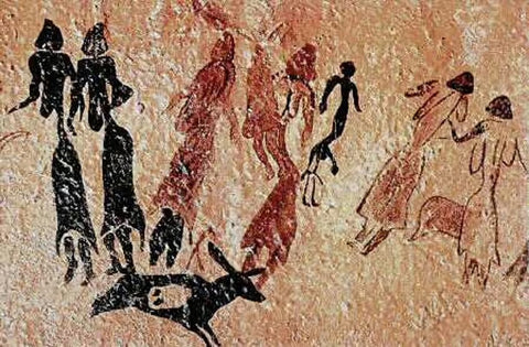 A prehistoric cave painting in black charcoal and red ochre depicts a group of women wearing dresses and dancing. In the foreground is a small animal with big ears - is it a slain animal from a hunt or a treasured pet laying down?