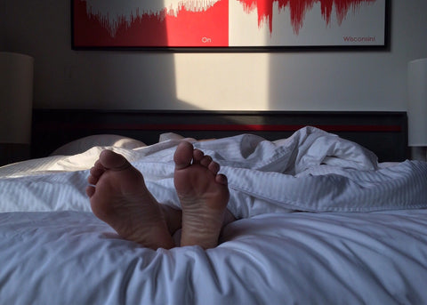 Person sleeping on their stomach with feet off the end of the bed