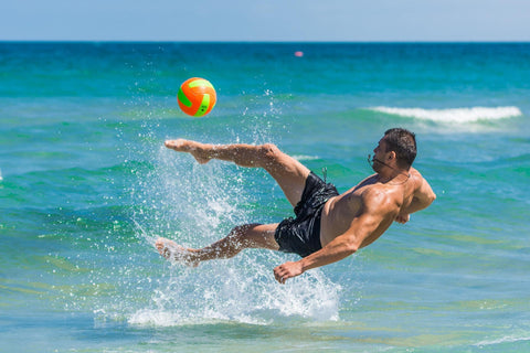 man playing with beach ball in the waves