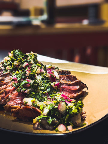 Sliced bavette steak on a plate topped with chimichurri sauce