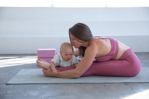 A new mom doing mommy and me yoga with her baby wearing sweat and milk's malibu seamless nursing sports bra