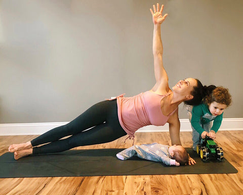 A new mom doing side planks wearing Sweat and Milk's Camelia Nursing Sports Tank Bra in pink. 