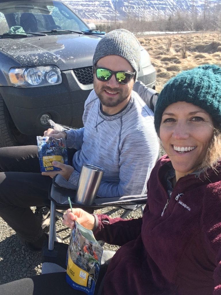 JJ and Josh smile as they eat Mountain House breakfasts from their pouches while sitting outside.
