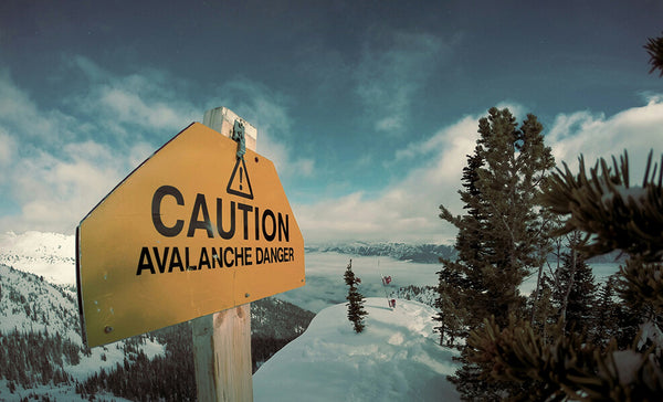 Caution Avalanche Danger sign on top of snow covered mountain peak