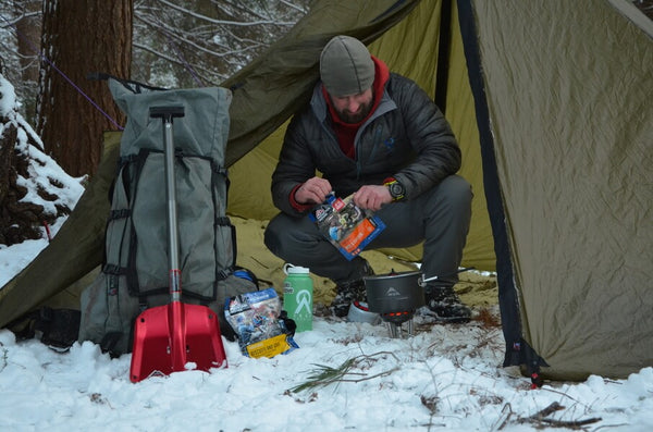 Clint Stout preparing Mountain House entree in tent during winter