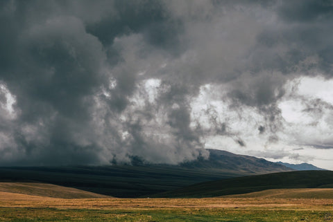 Rain clouds over mountain foothills & valley.