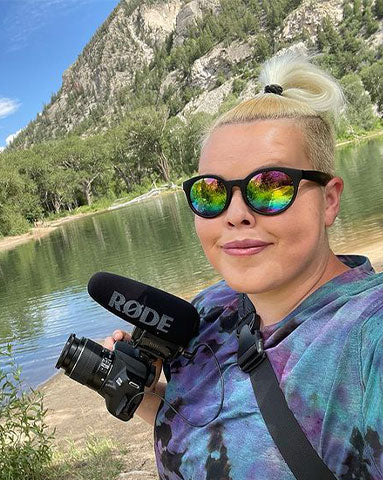 Crystal holding camera and taking a selfie near a mountain lake