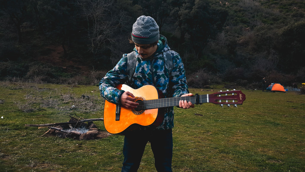 man playing guitar at camp