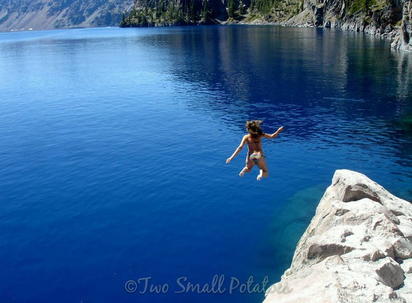 Girl jumping off cliff into Crater Lake