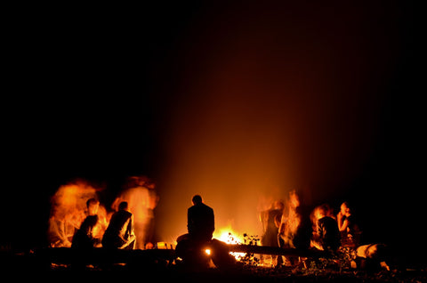Group of people sitting around a campfire.