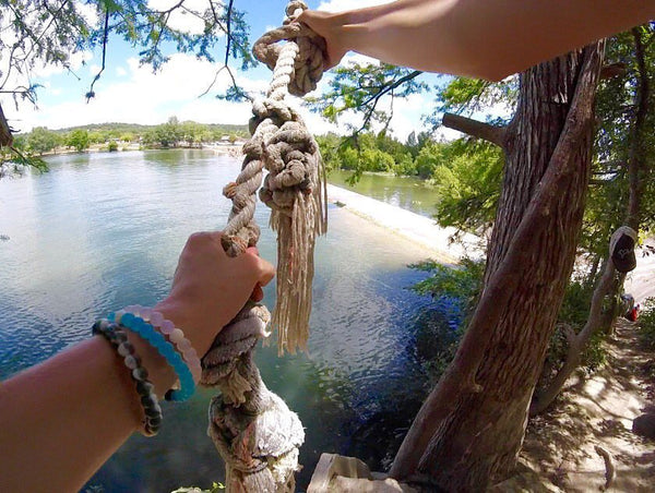 Person holding rope getting ready to swing into lake.