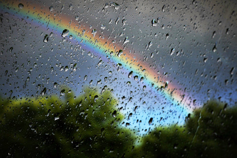 Rainbow behind wet glass.