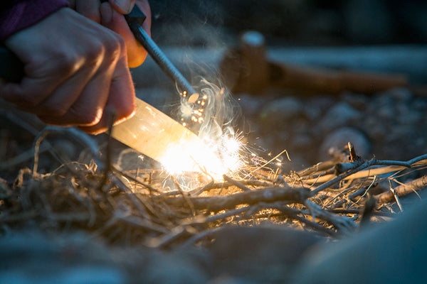 Person starting a small fire with twigs