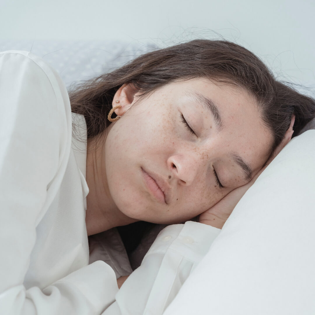 Une jeune femme est allongée sur le côté, les yeux fermés.