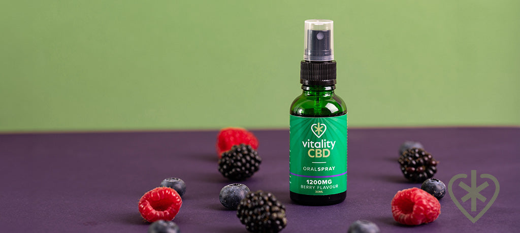 Bottle of berry flavour CBD oil spray, surrounded by berries