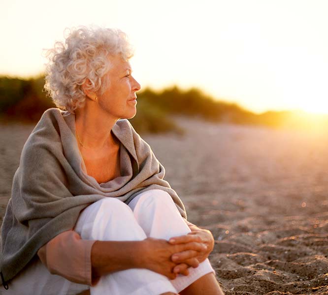 Elderly woman relaxing on beach