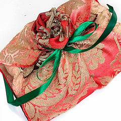 A pretty gift wrapped in red material and a green ribbon - Parade Handmade