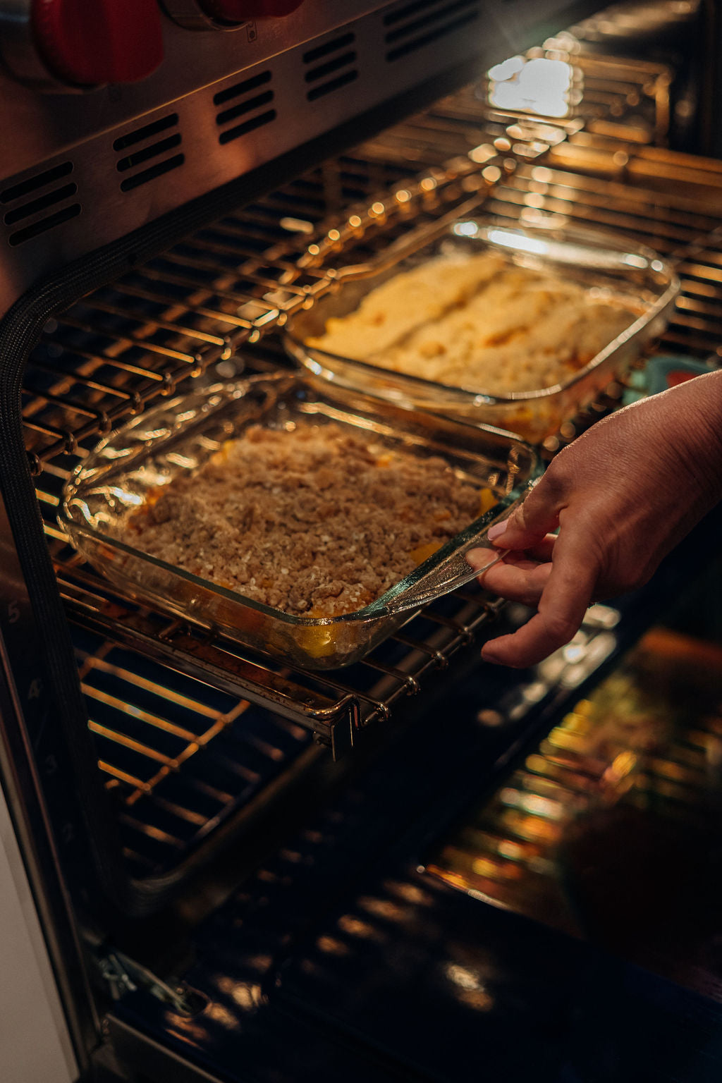 Michelle Sirles of Rendleman Orchards places homemade peach crisp next to a peach cobbler in the oven.