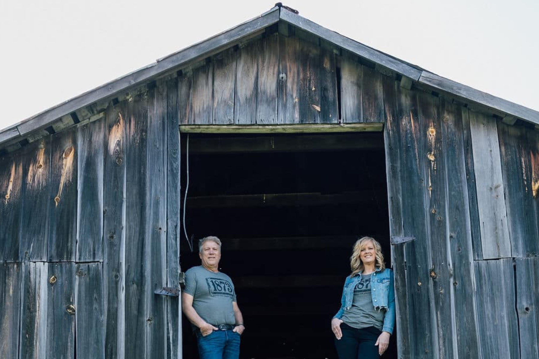 Image of Wayne and Michelle Sirles standing at the top window opening of old barn at Rendleman Orchards.