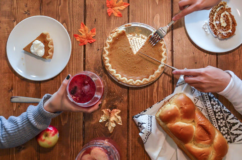 tradition thanksgiving holiday gathering; pumpkin pie and wine and loaf of bread on wooden table.