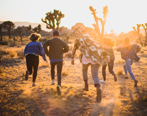 five people running towards the sun; running away from the viewer