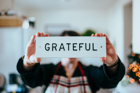 holding up sign displaying the word GRATEFUL