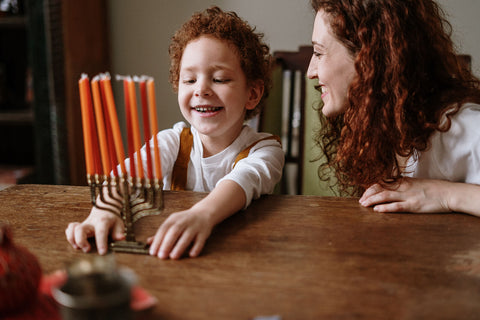 Mom and son lighting menorah for Hanukkah