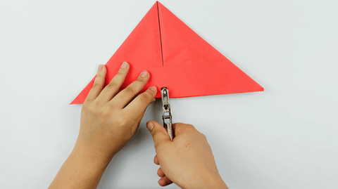 Hole punching the bottom of the paper hat for string to attach