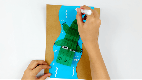 Drawing white water caps on the blue paper to create water for paper nile crocodile